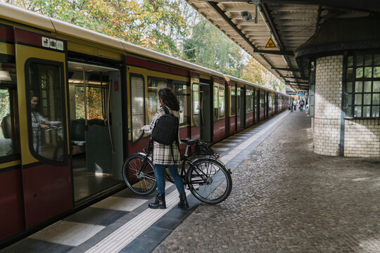 Woman with bicycle entering an underground train, Berlin, Germany