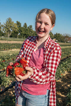 Smiling teenager girl holds fresh fruit in a farm field