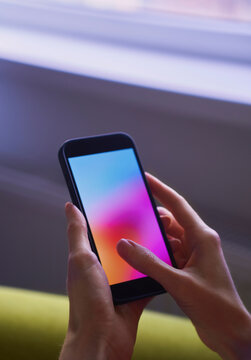 Woman holds a smartphone with a colorful gradient screen indoors