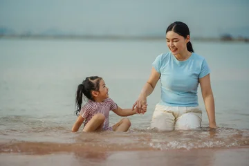 happy preschool child girl playing water with her mother on sea beach in Pattaya, Thailand © geargodz