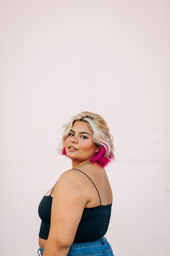 Plus size woman standing against pink wall