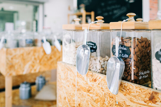 Glass jars with almonds and metal scoops in zero waste grocery store