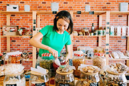Entrepreneur scooping food from a jar in a zero waste grocery store