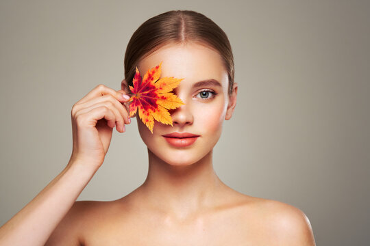 Portrait of beautiful young woman with autumn leafs. Healthy clean fresh skin natural make up beauty eyes