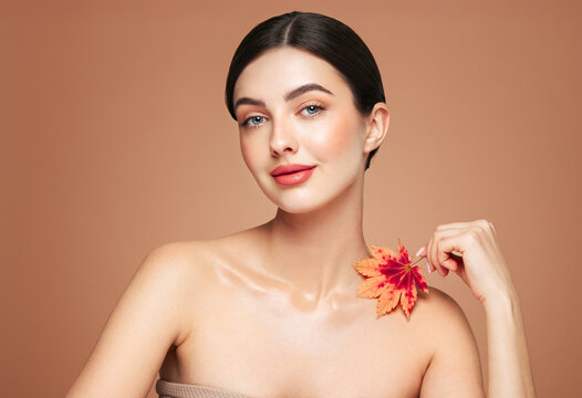 Portrait of beautiful young woman with autumn leafs. Healthy clean fresh skin natural make up beauty eyes