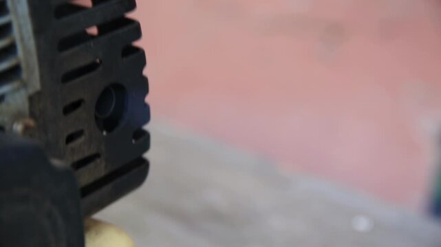 Close-up view of metal engine part emitting smoke from circular exhaust port, illustrating working mechanism with industrial power and emission.