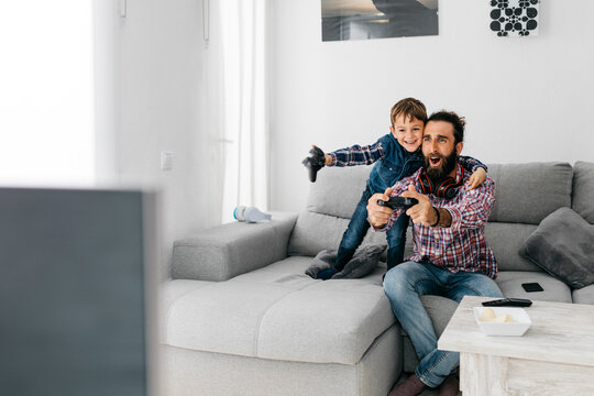 Excited father and son playing computer game at home