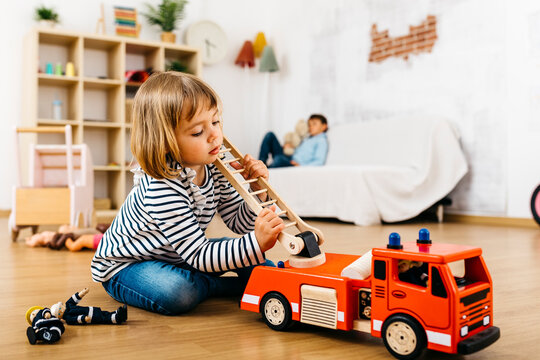 Little blond playing with a wooden fire truck