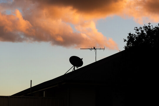 aerial and dish on rooftop with sunset clouds in sky