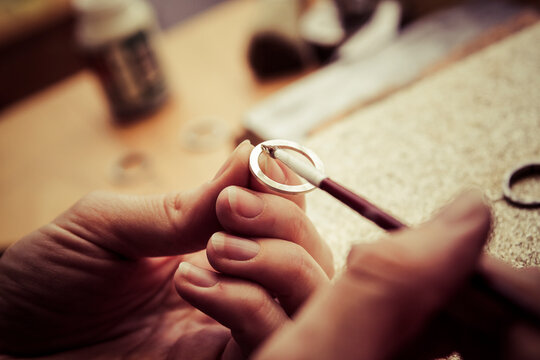 Goldsmith working on wedding rings, applying chemical on surface