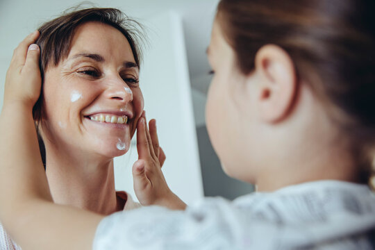 Daughter putting facial cream on mother?s face