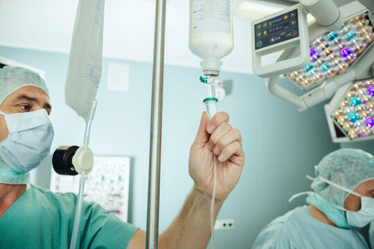 Operating room nurse checking the drip of an IV bag during surgery