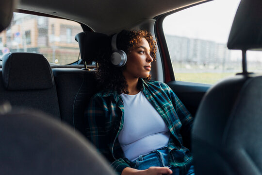 Thoughtful woman wearing bluetooth headphones in car