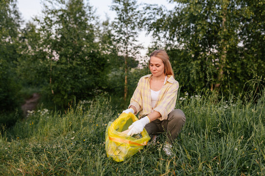 Woman volunteering outdoors to clean up plastic waste