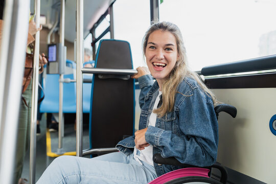 A smiling woman in a wheelchair travels on public transport