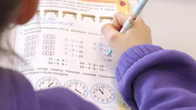 A student solves mathematics homework exercises in a colorful workbook using a pencil, illustrating academic practice, early education, focused learning, and development of logic skills