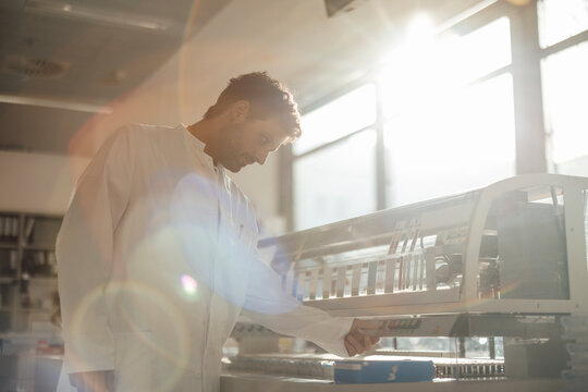 Scientist analyzing information on lab machine in hospital