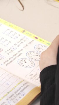 A student solving math exercises in a workbook at desk, demonstrating academic focus, diligent learning practice, and school education in a quiet classroom environment setting. Vertical