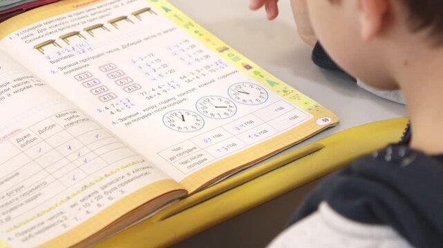 A young schoolchild uses a purple mechanical pencil to solve math problems in a workbook, capturing the focus and effort of early childhood education in a modern home study setting