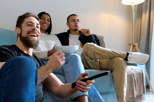 Cheerful friends spending leisure time watching TV at home