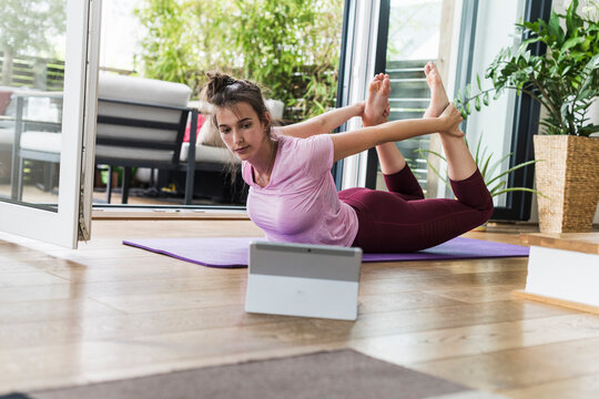 Woman practices yoga at home using a tablet