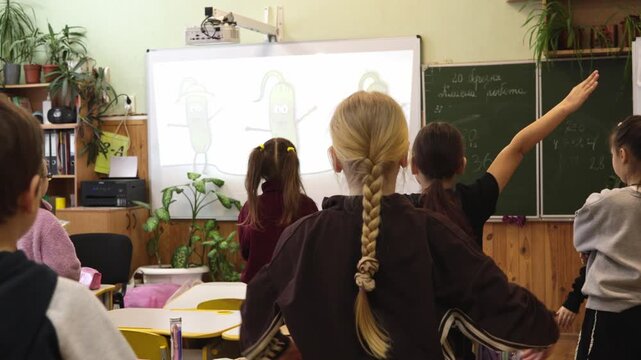 Young school children perform physical exercise movements in a classroom during a lesson, fostering active learning and student wellness within a supportive academic school environment