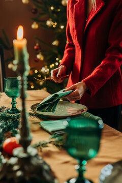 Woman sets a decorated table for a festive Christmas dinner