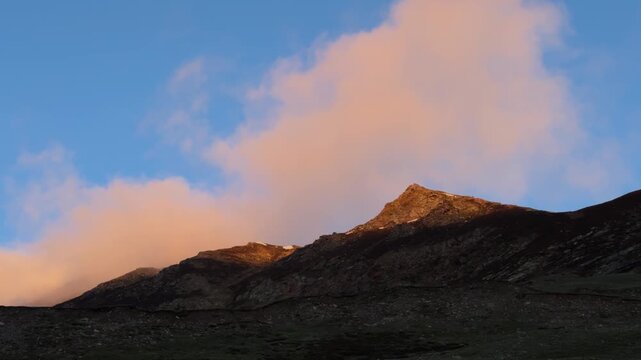 4K Landscape shot of orange clouds above the Himalayan mountain peak during the sunset as seen during the Ghepan Ghat Lake Trek near Sissu village in Lahaul, Himachal Pradesh, India. Nature background
