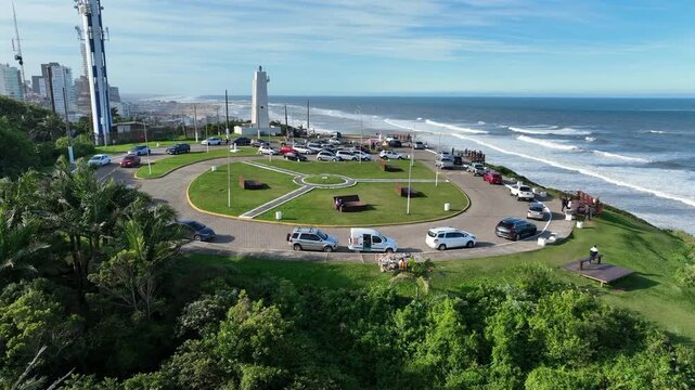 Morro do Farol lighthouse orbit counterclockwise on the Torres coastline with ocean and green hill