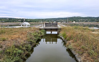 Fototapeta premium Symmetrical reflection of traditional wooden sluice gate in salt pan canal at Secovlje Salina, Slovenia