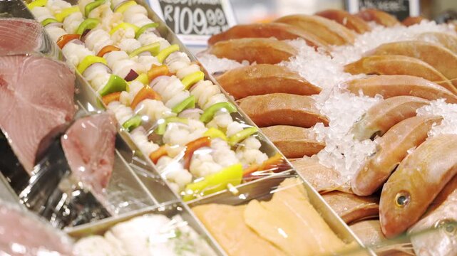 Whole fish on ice sit beside colorful seafood and vegetable skewers in a bright retail display case.