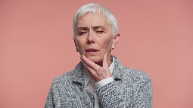 Senior Woman Suffering From Severe Tooth Pain on Pink