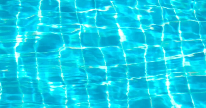 clear blue swimming pool water with shimmering reflections and tiled pattern, gentle moving ripples, abstract summer background ideal for travel, leisure, relaxation, wellness, refreshing, luxury pool