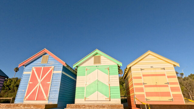 Three Colorful Brighton Beach Bathing Boxes Under Clear Blue Sky