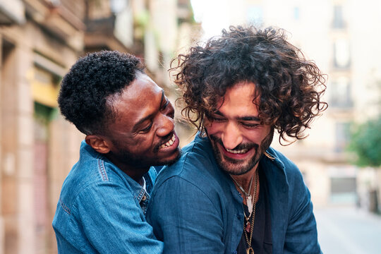 Smiling gay man embracing male friend from behind