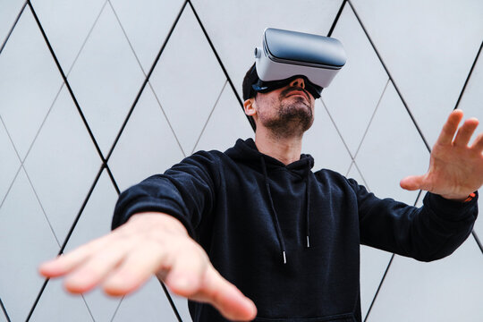 Man wearing Virtual reality headset while gesturing near wall