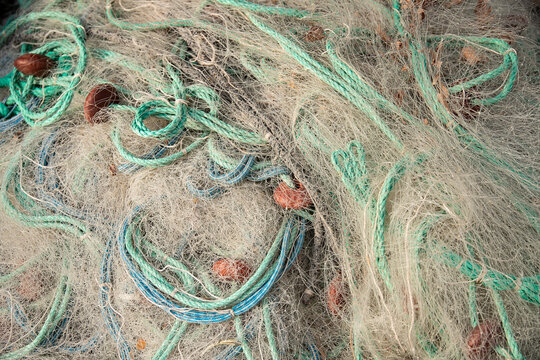 Fishing nets in a tangled pile with ropes and colourful floats, symbolizing the fishing industry