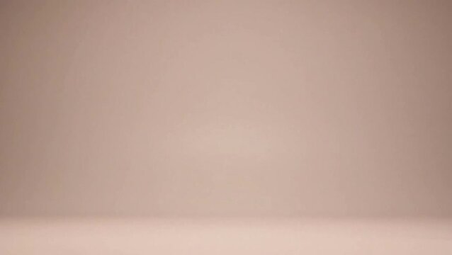 Empty light brown studio background with seamless curved wall and floor for product display.