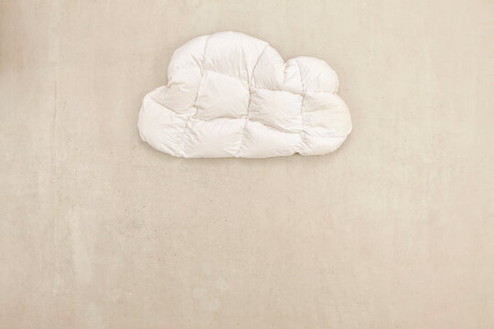 A white cloud pillow lies on a concrete floor in a studio