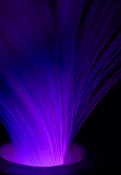 Glowing purple optic fiber cables illuminate the dark background