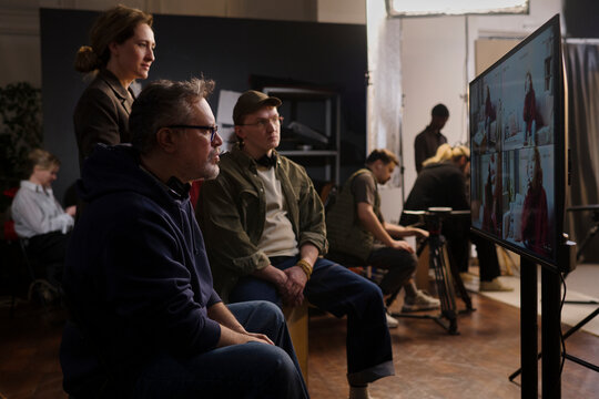 Film director and crew review playback footage on set indoors
