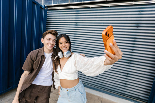 A man and a woman take a selfie with a smartphone outdoors