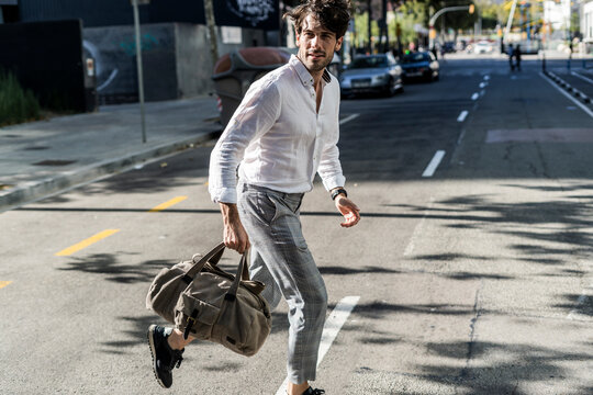 Young man in the city on the go crossing street