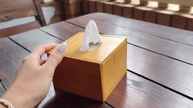 Female Hand Pulling Wooden Tissue Box Closer on Cafe Table