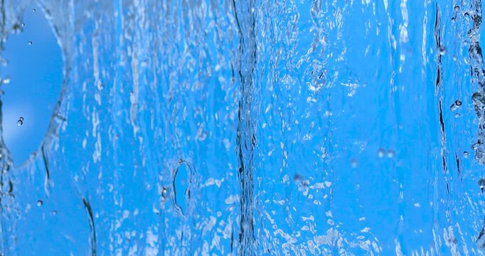 Flowing water texture with bubbles against a blue background. Clean, fresh, dynamic motion ideal for nature, wellness, environmental and background projects, close-up