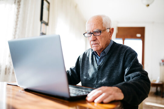 Portrait of serious looking senior man using laptop at home