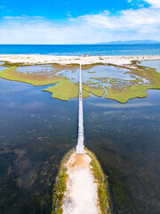 Fototapeta premium Wooden pier crossing saltwater lagoon towards ionian sea