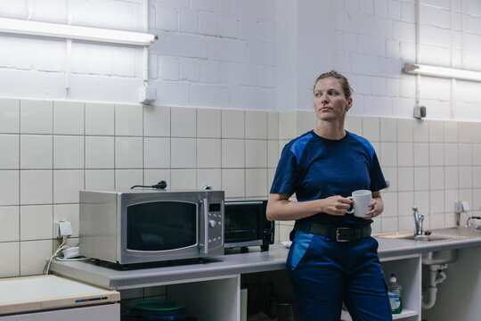 Young woman working in high tech enterprise, taking a break, drinking coffee
