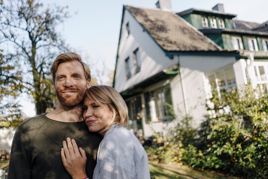Smiling affectionate couple in garden of their home