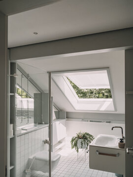 Bright modern attic bathroom with skylight and white tiles